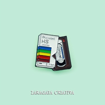 Pin em forma de cassete de vídeo vintage colorido sobre fundo verde claro