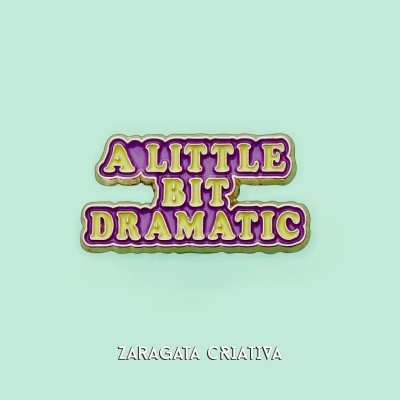 Chapa metálica com texto 'A LITTLE BIT DRAMATIC' em esmalte roxo e amarelo sobre fundo verde