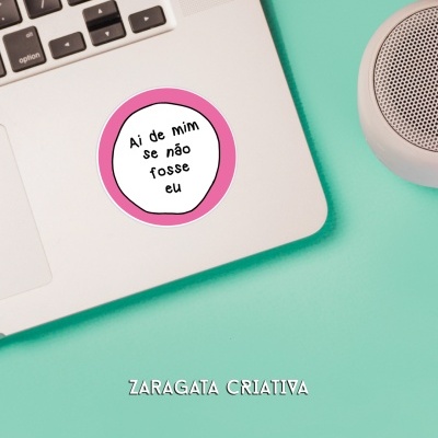 Computador portátil com autocolante junto a coluna portátil sobre mesa azul-turquesa