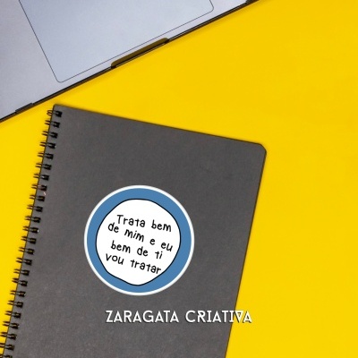 Caderno cinzento com autocolante distintivo em fundo amarelo e portátil cinzento