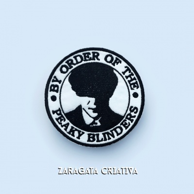 Patch redondo preto e branco com texto e figura de homem de chapéu sobre fundo azul claro