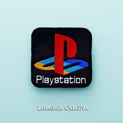 Patch bordado com o logo da PlayStation e texto, sobre superfície azul clara