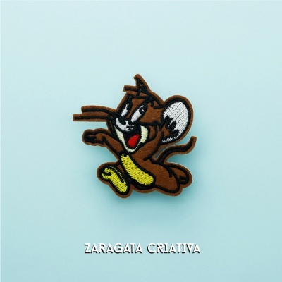 Broche ou patch bordado personagem desenho animado castanho e amarelo em fundo azul.