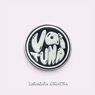 Emblema bordado preto e branco com texto Vai Fundo sobre fundo rosa