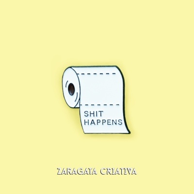 Rolo de papel higiénico branco com texto SHIT HAPPENS sobre fundo amarelo