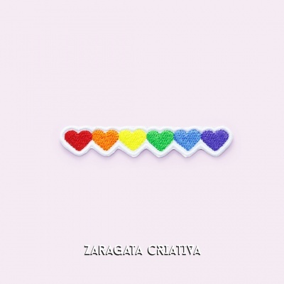 Emblema bordado com sete corações coloridos em linha sobre fundo rosa pálido