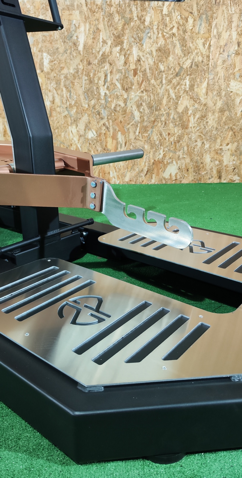 Base de equipamento de treino com placas metálicas e logótipo em piso de relva artificial