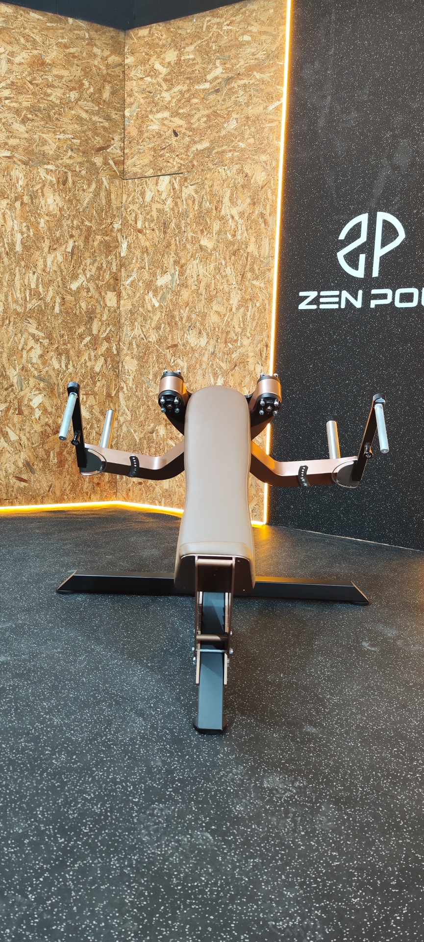 Máquina de ginásio em ambiente com paredes de madeira e painel preto com texto ZEN PO