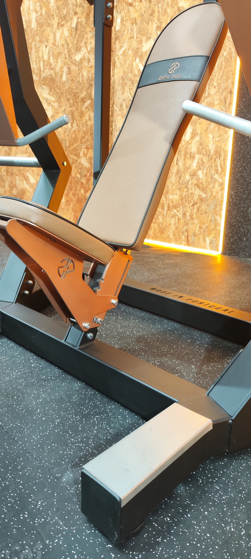 Banco de exercício com estofado bege e estrutura metálica preta e laranja numa sala de ginásio