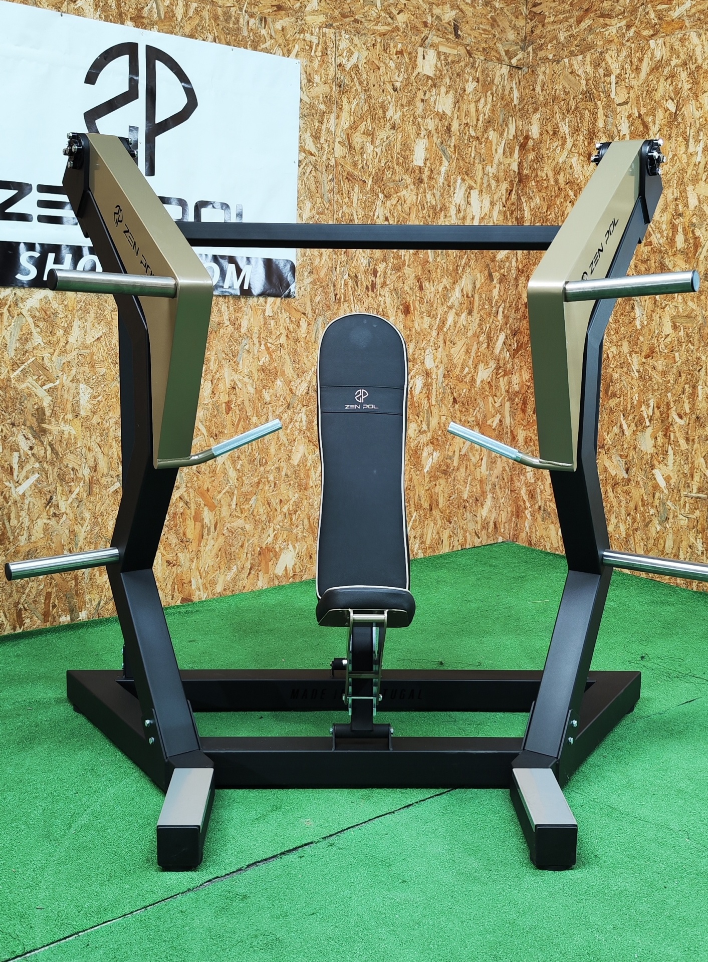 Máquina de supino inclinado preta e dourada com banco acolchoado e logotipo em fundo de madeira