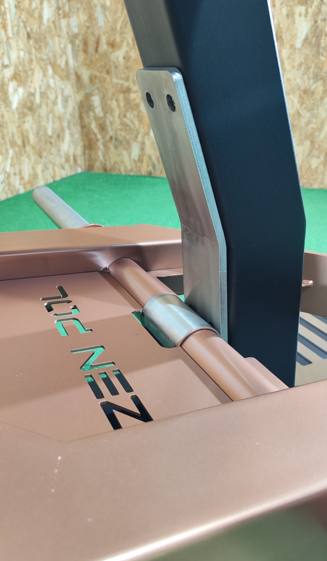 Estrutura metálica bronze com peça preta e texto recortado ZEPNIL