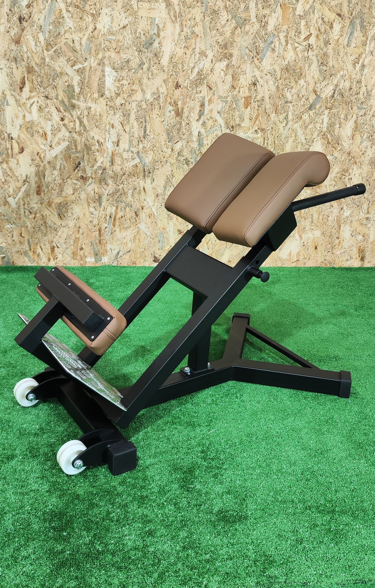 Equipamento de ginásio para exercícios lombares com estofos castanhos e estrutura preta