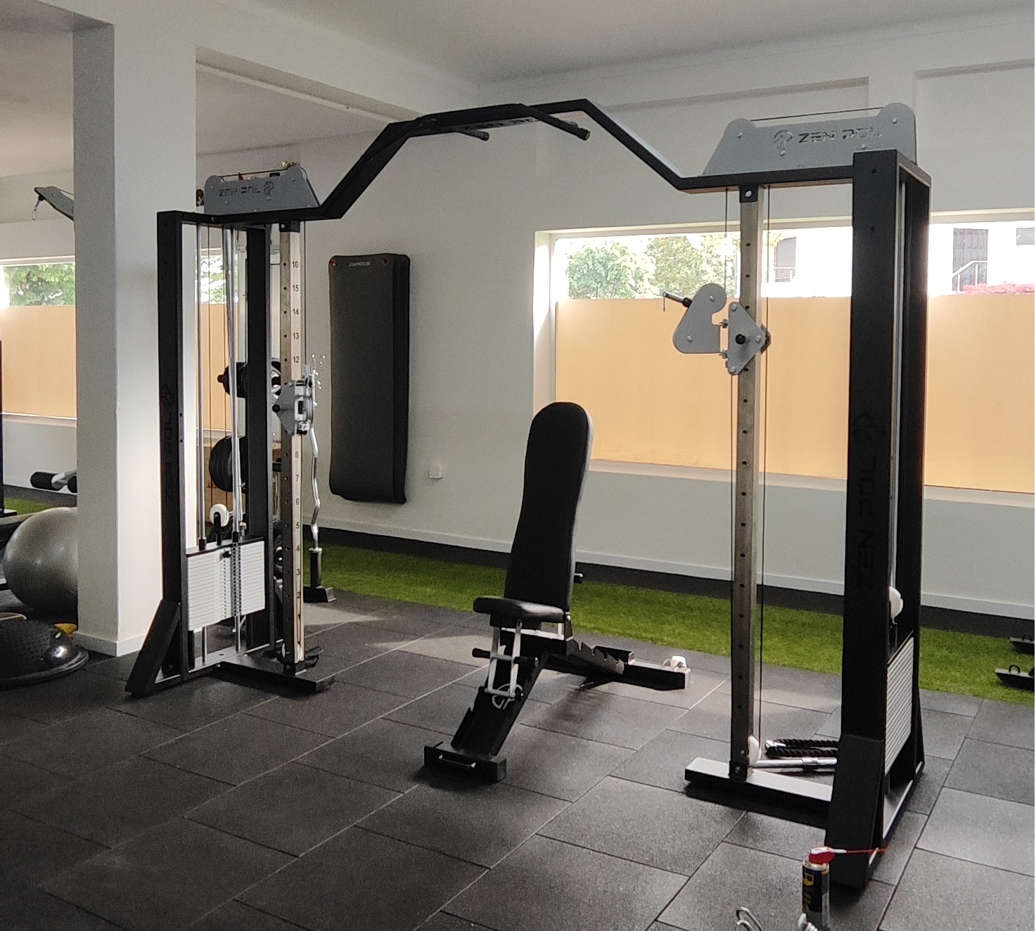 Aparelho multifuncional de treino preto com banco estofado numa sala de ginásio