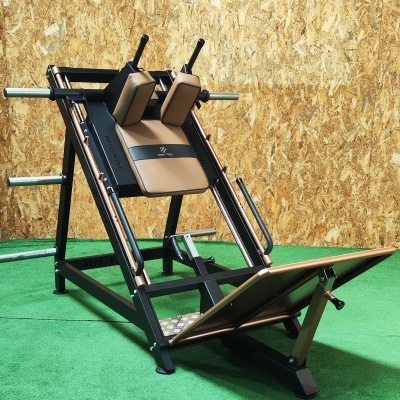 Equipamento de ginásio para treino de pernas preto e castanho num chão verde