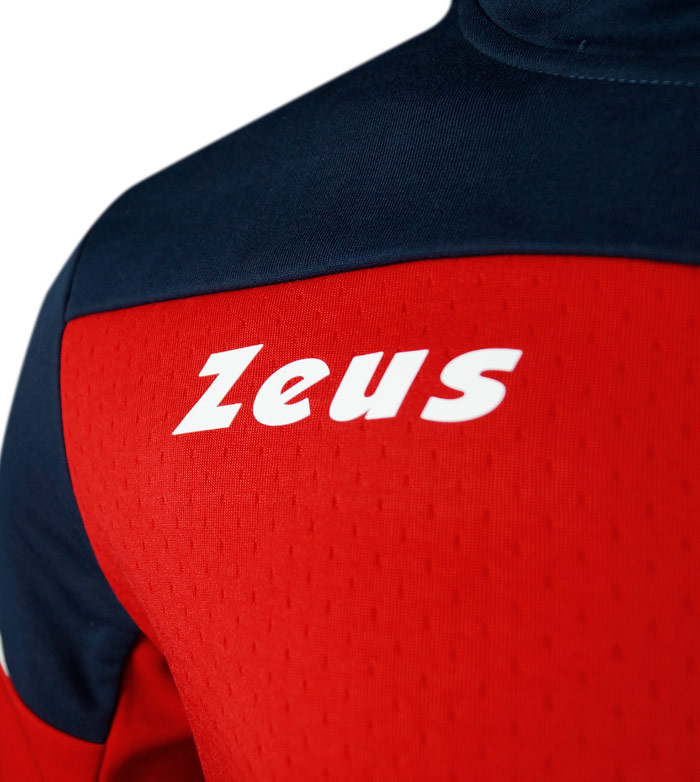 Pormenor de peça de vestuário desportivo vermelha e azul com texto branco Zeus