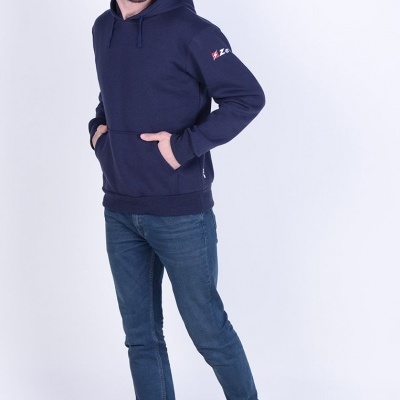 Homem com hoodie azul escuro, jeans e ténis azuis frente a fundo branco