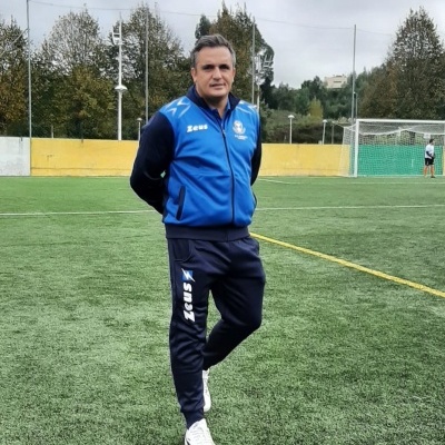 Homem em fato de treino azul e preto no campo de futebol