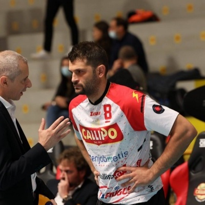 Jogador de voleibol a conversar com treinador num pavilhão desportivo.