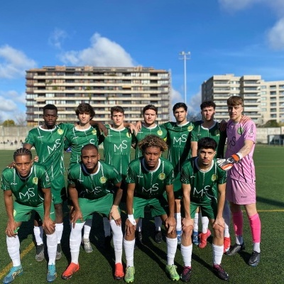 Equipa de futebol com camisolas verdes e guarda-redes de rosa no campo