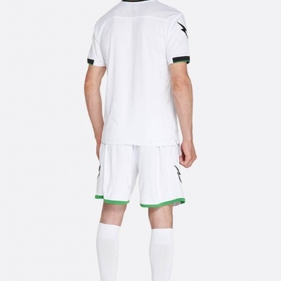 Jogador de futebol vestido com equipamento branco e chuteiras amarelas visto de costas