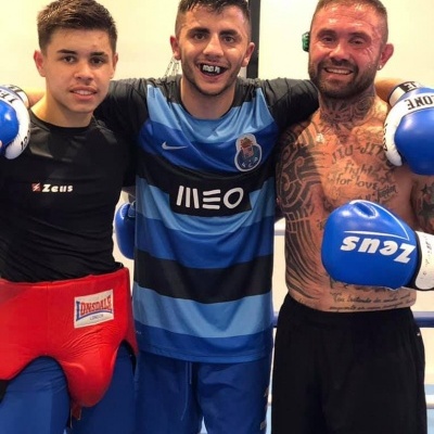 Três homens com equipamentos de boxe em ringue, luvas azuis Zeus, protetor vermelho Lonsdale, camisola azul e preta FC Porto.