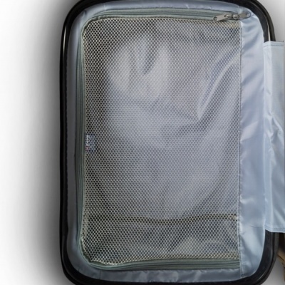 Mala de viagem preta aberta com interior cinza e rede com fecho.