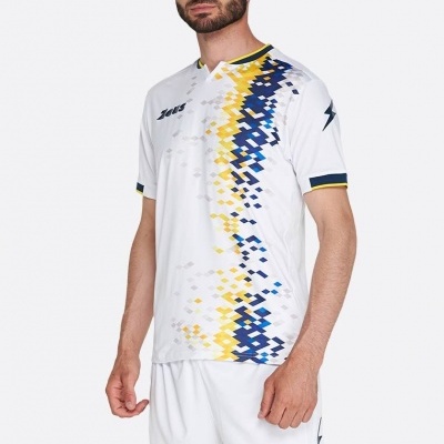 Camisola desportiva branca com padrão pixelado amarelo e azul e calções brancos com texto Zeus