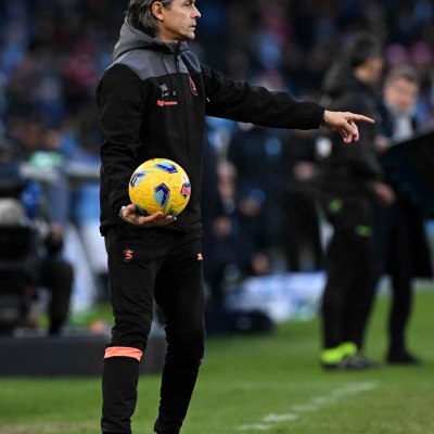 Homem de roupa desportiva preta com bola de futebol amarela no estádio
