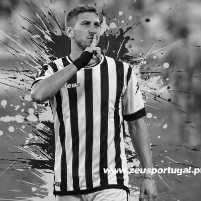 Homem com camisola desportiva riscada preta e branca, fazendo gesto de silêncio