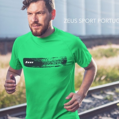 Homem a correr com camiseta verde Zeus junto a linha férrea