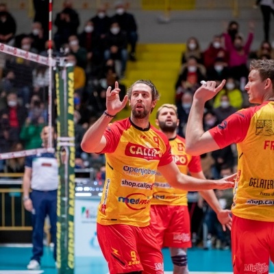 Jogadores de voleibol com camisolas amarelas e vermelhas num jogo interior