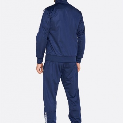 Homem de costas com fato de treino azul escuro e ténis azuis em fundo branco