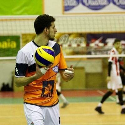 Jogador segurando bola de voleibol num campo interior