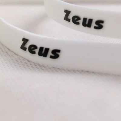 Fitas brancas com texto 'Zeus' a preto sobre tecido branco