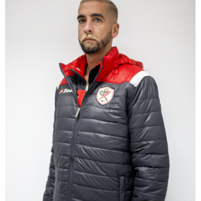 Homem com casaco acolchoado cinza escuro, vermelho e branco com emblema e texto JMT.