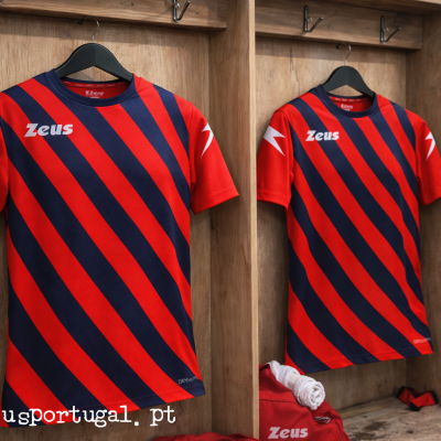 Camisolas desportivas vermelhas e azuis com riscas diagonais penduradas em balneário de madeira