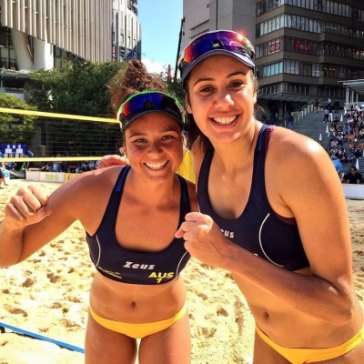 Duas jogadoras de voleibol de praia em campo de areia com tops e calções desportivos