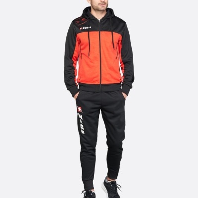 Homem a vestir fato de treino preto e vermelho da marca ZEUS com ténis pretos.