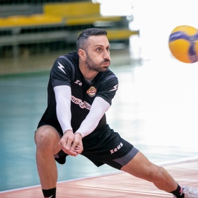 Jogador de voleibol em ação num ginásio com camisola preta e calções pretos
