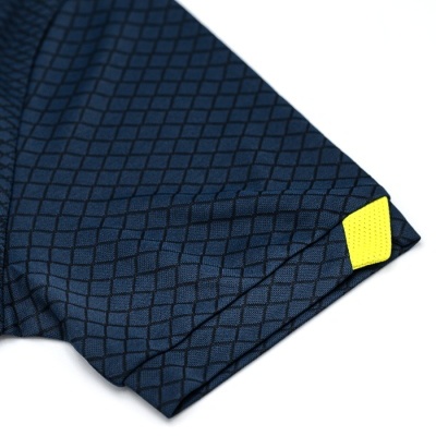 Manga de t-shirt azul escura com padrão de losangos e etiqueta amarela