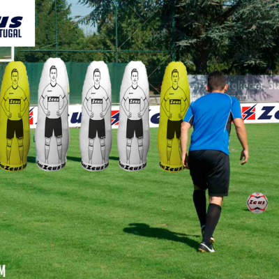 Campo de futebol com homem a chutar bola e manequins de treino Zeus insufláveis