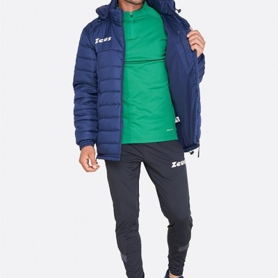 Homem a vestir roupa desportiva da marca Zeus com casaco azul, camisola verde e calças pretas em fundo branco