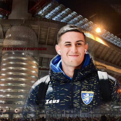 Jovem com roupa desportiva azul-escura e auriculares em frente a estádio iluminado à noite