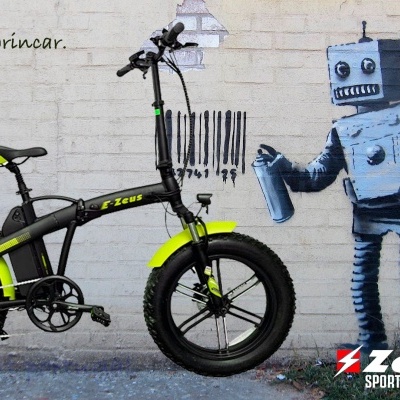 Bicicleta preta e amarela ao lado de grafite de robô azul numa parede com texto e logo Zeus