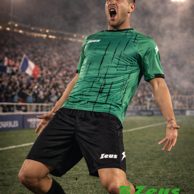 Jogador de futebol em camisola verde e calções pretos no campo de futebol