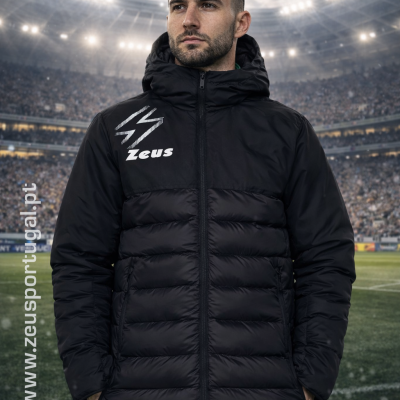 Homem com casaco acolchoado preto e logotipo Zeus num estádio de futebol