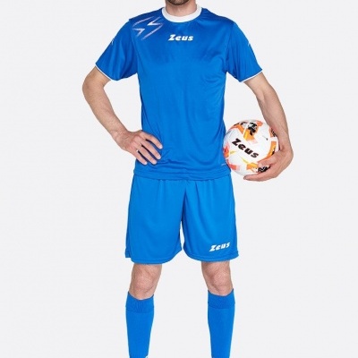 Homem vestido com equipamento de futebol azul segurando uma bola da marca Zeus