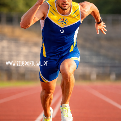 Atleta a correr com fato de corrida azul e amarelo numa pista desportiva