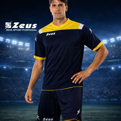 Equipamento de futebol azul escuro com detalhes amarelos e brancos, logotipos Zeus, modelo em estádio iluminado