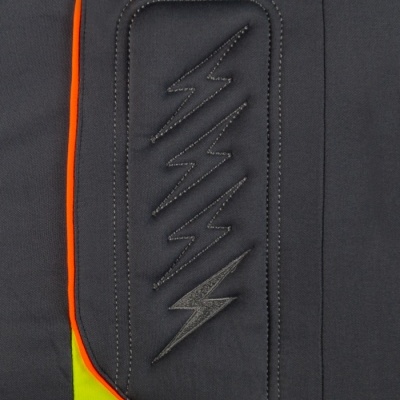 Pormenor de tecido azul escuro com costura de relâmpagos e aplicações amarelas e laranja